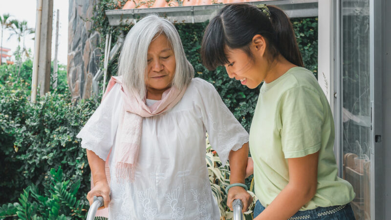 asian woman using walker with grandchild